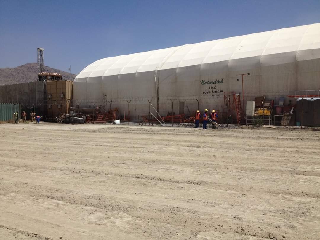 Workers beside a large temporary industrial structure
