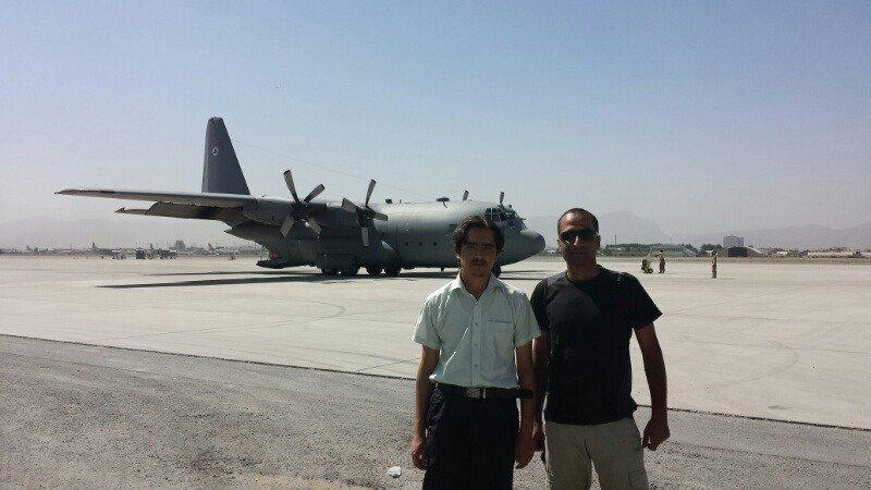 Two people on an airfield with a cargo aircraft in the background
